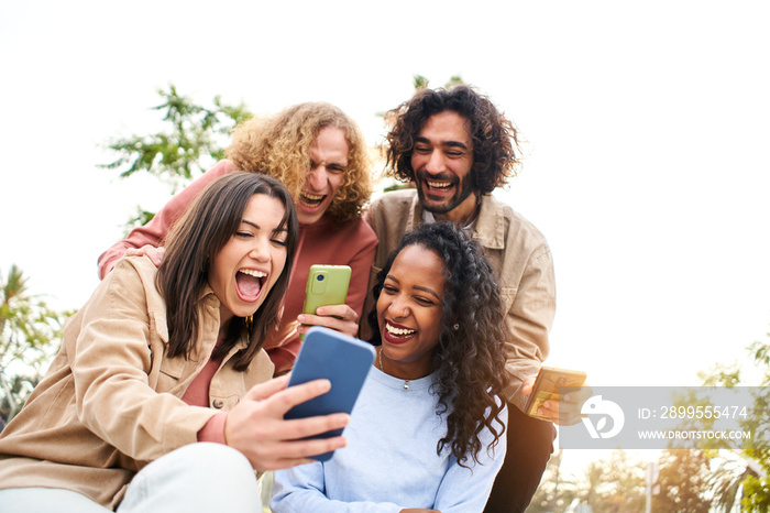 Happy friends watching screen mobile phone with a surprised face and smiling. Young adult people using smartphone and having fun.