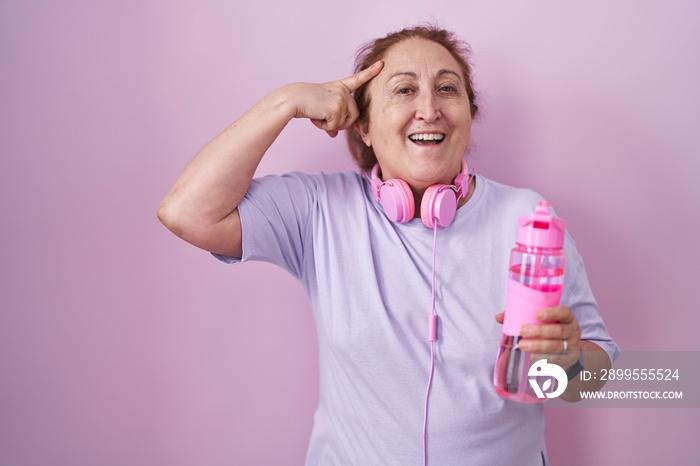 Senior woman wearing sportswear and headphones smiling pointing to head with one finger, great idea or thought, good memory