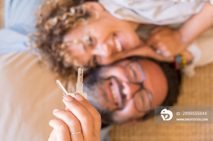 Happy young couple show new own house keys excited to move together, smiling loving adult husband and wife overjoyed first time buyers relocate rent shared apartment