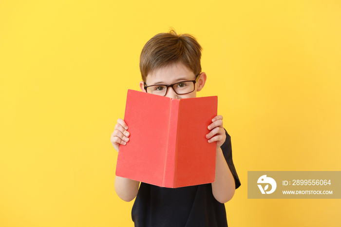 Little boy reading book on color background