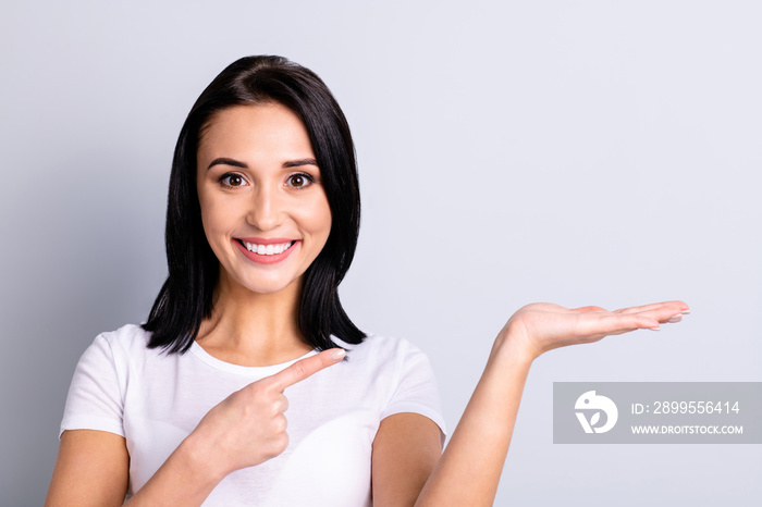 Close-up portrait of her she nice attractive lovely shine winsome confident charming cheerful cheery girl holding object on palm copy empty blank space isolated over light gray pastel background