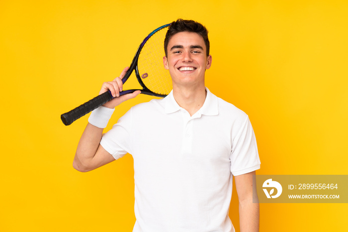 Handsome teenager tennis player man isolated on yellow background playing tennis