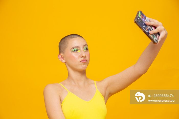 Studio shot of girl with neon colored make-up taking selfie