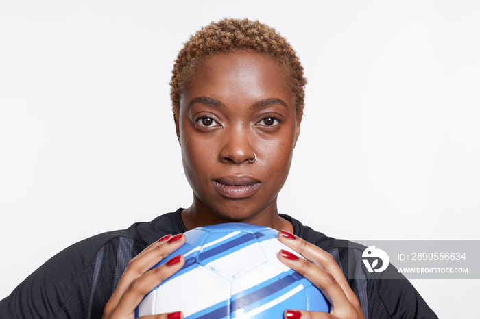 Studio portrait of female soccer player with ball