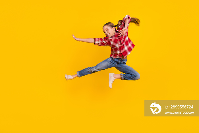 Photo of cool shiny schoolkid dressed plaid shirt jumping high practicing karate isolated yellow color background