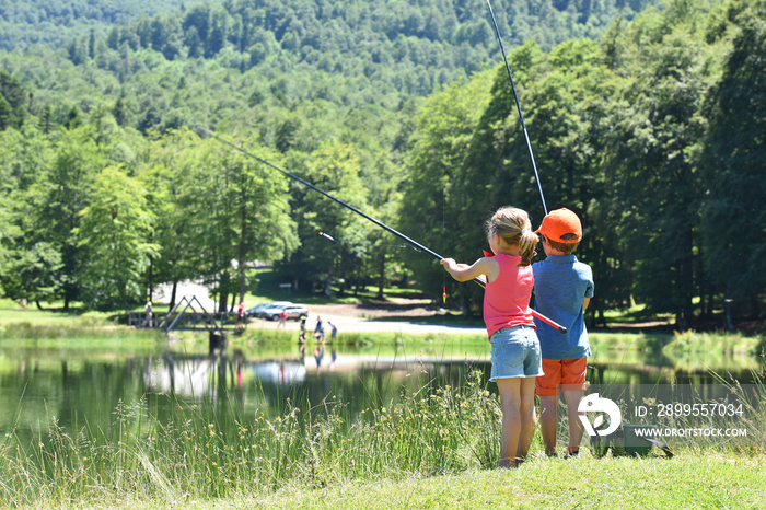 Kids fishing by mountain lake in summer