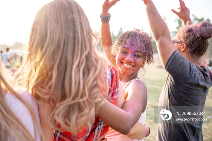 African American young woman covered in colorful powder with friends at holi festival