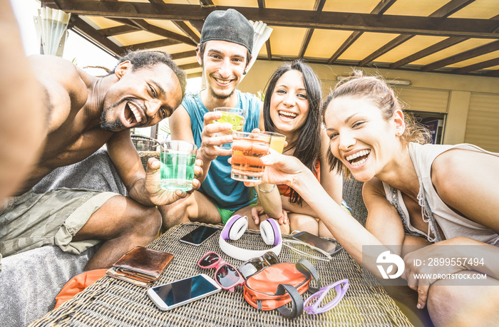 Multiracial happy friends group taking selfie and having drunk fun with cocktail at beach resort - Summer concept and multi ethnic friendship at bar restaurant - Sunny afternoon filtered color tones