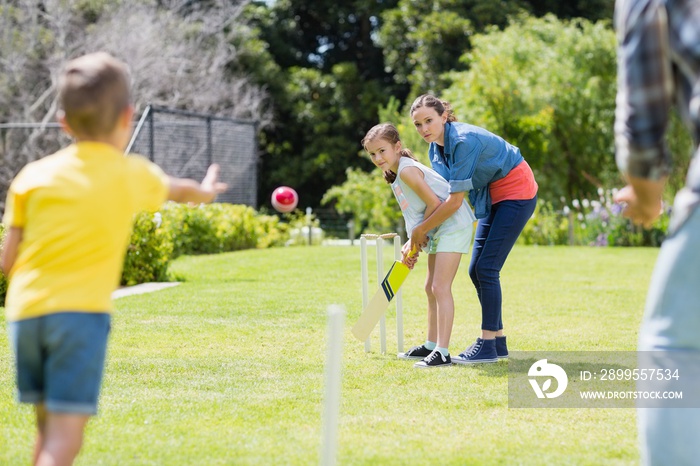 Family playing cricket in park