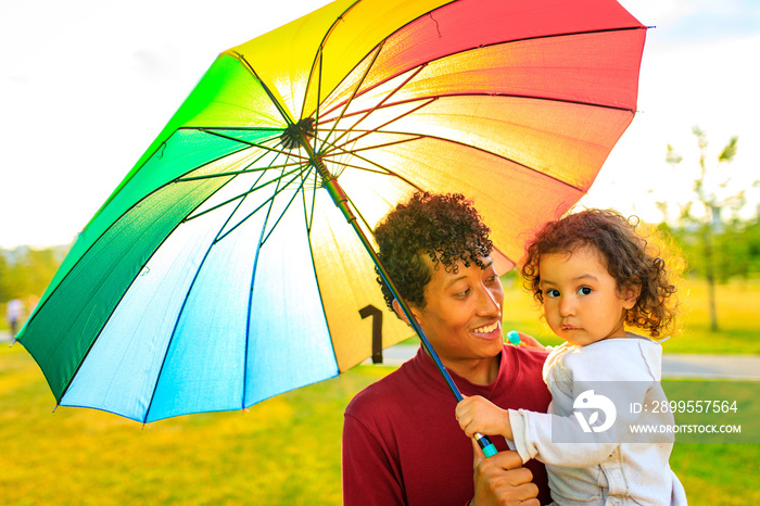 mixed race family covering from the sun under the bright umbrella