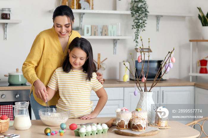 Little girl and her mother making dough for Easter cake in kitchen