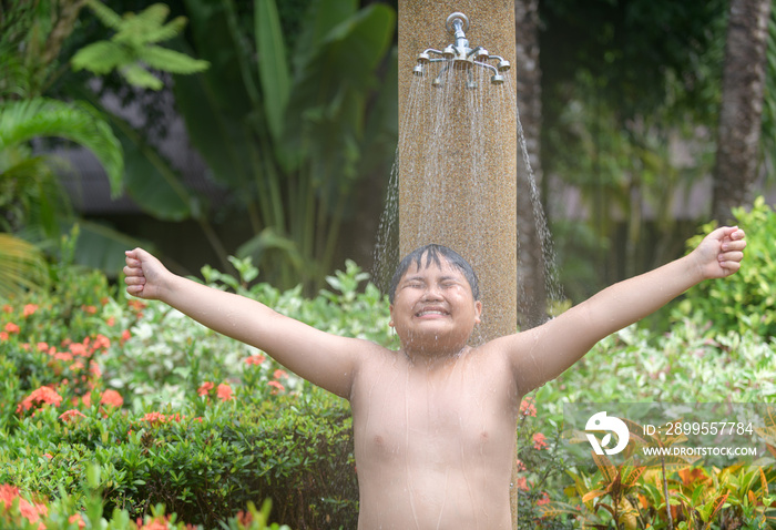 Happy obese boy taking shower before swimming,