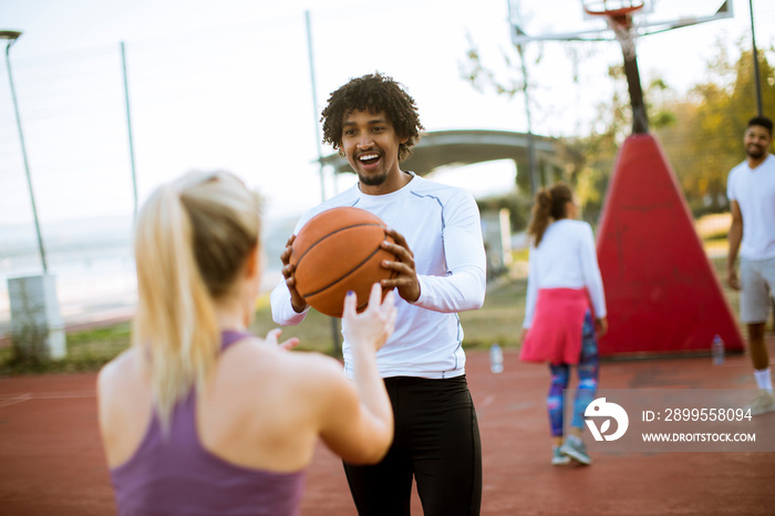 Multiracial couple playing basketball on outdoor court