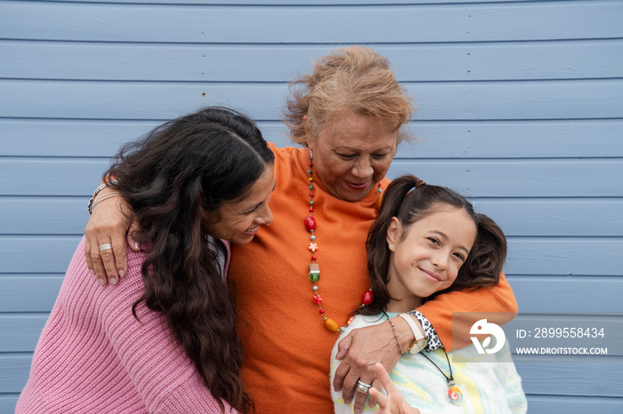 Portrait of grandmother, mother and granddaughter against blue wall