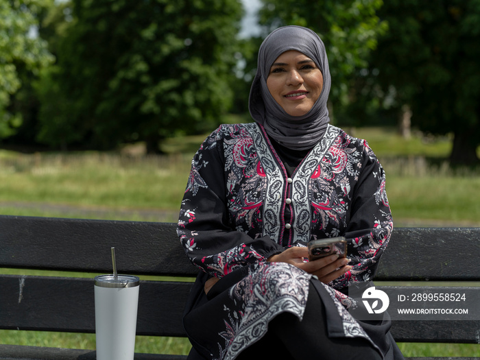 UK,Sutton,Portrait of woman in headscarf sitting on bench in park