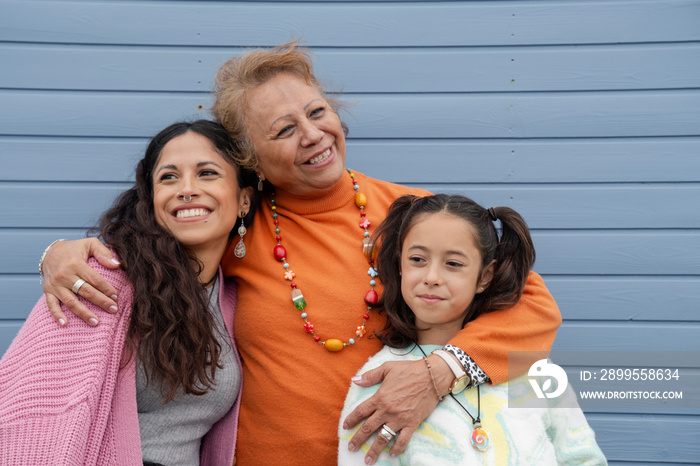 Portrait of grandmother, mother and granddaughter against blue wall