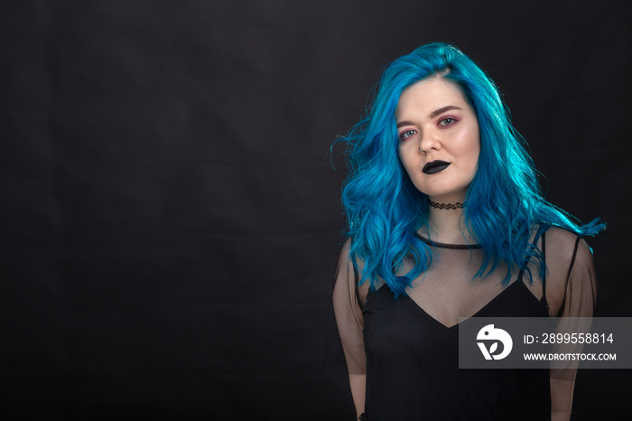 Style, fashion and hair concept - close-up portrait of young woman in black dress with blue hair on black background