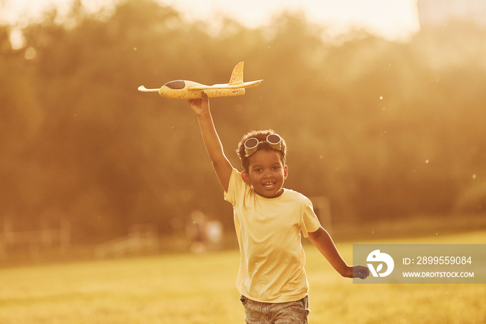 With pilot sunglasses. African american kid have fun in the field at summer daytime