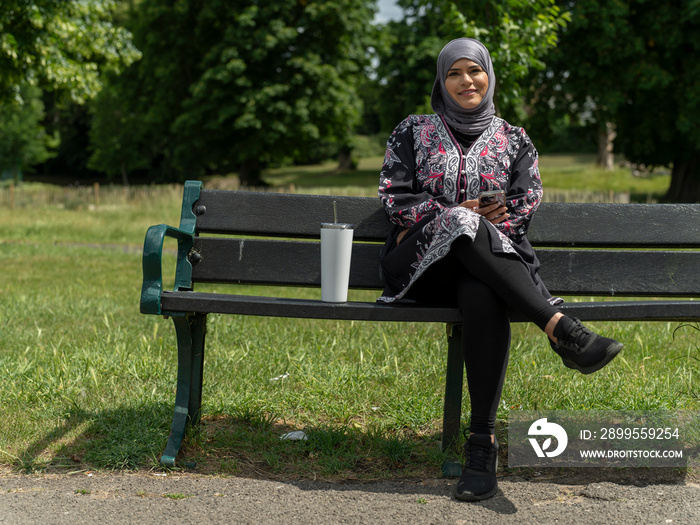 UK,Sutton,Portrait of woman in headscarf sitting on bench in park