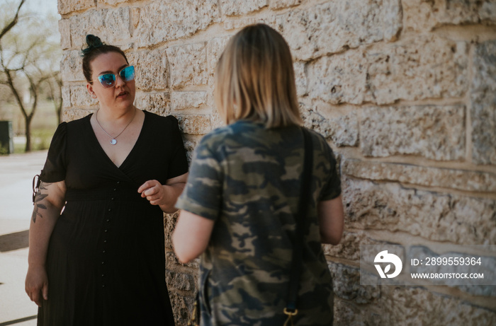 2 women leaning against wall talking