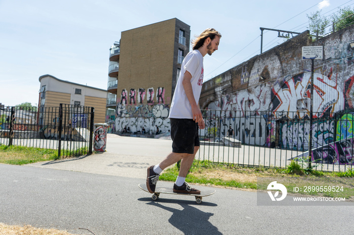 Young man skateboarding on footpath