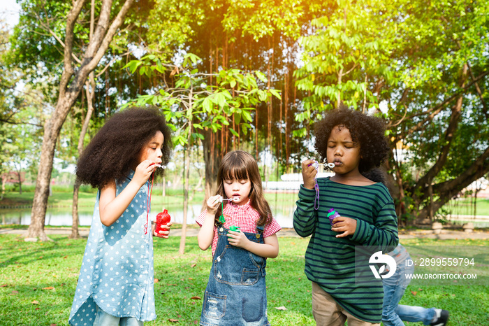 Happy children in a field trips and playing blowing bubbles together in the green park, Outside school education concept