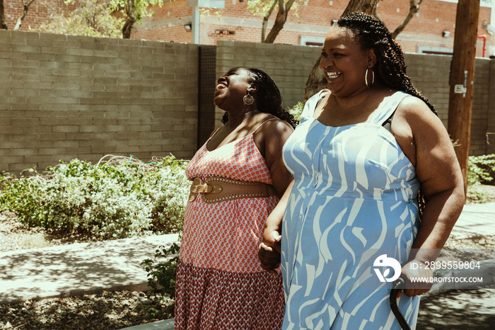 2 African American women walk and smile outside