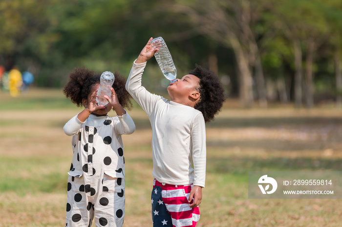 African American children drinking water while playing  in the park