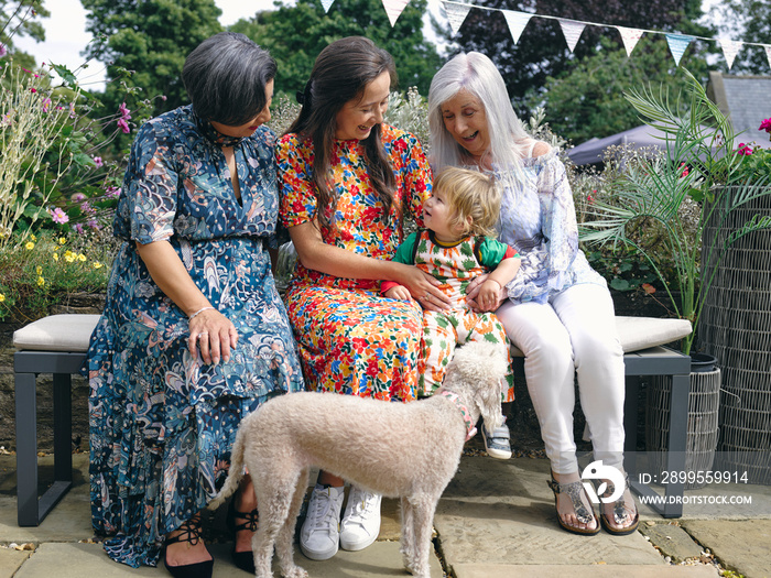 Multi-generation family with baby boy sitting on bench