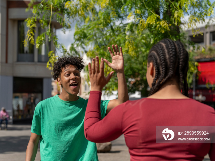 Two friends giving high-five in city street