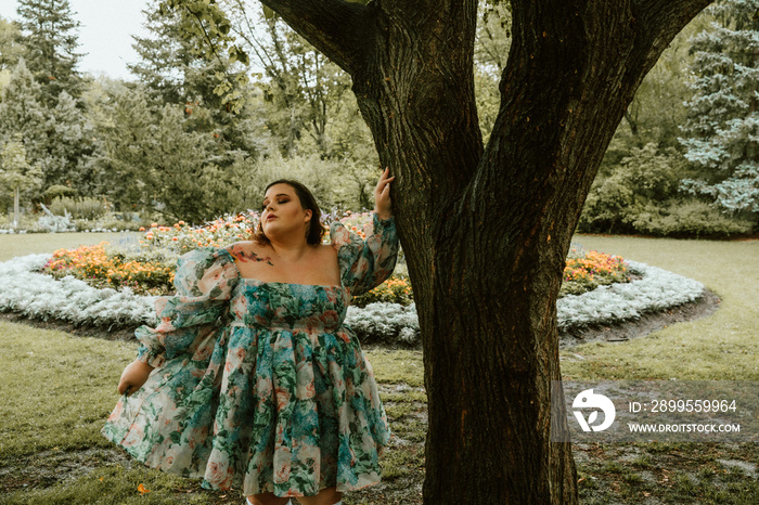 portrait of a plus size woman standing against a tree