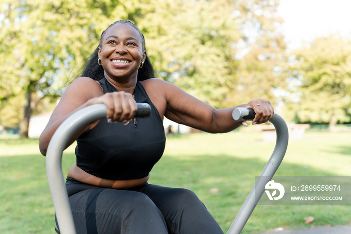 Smiling young woman exercising in outdoor gym