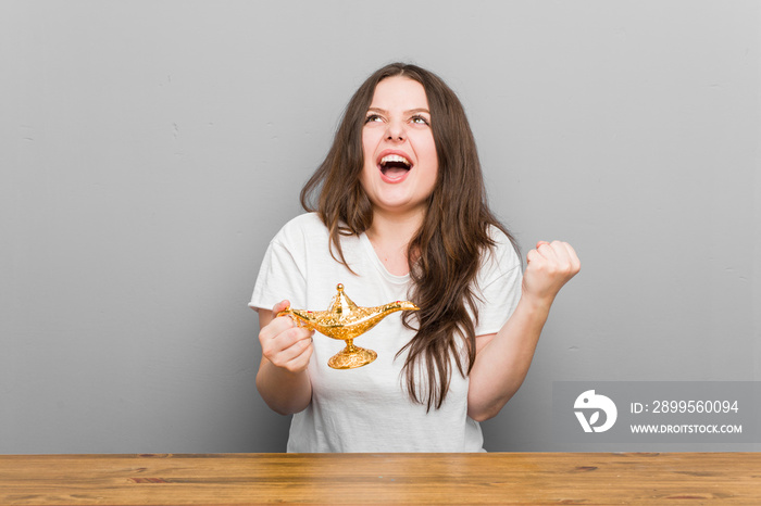 Young plus size curvy woman holding a magic lamp cheering carefree and excited. Victory concept.