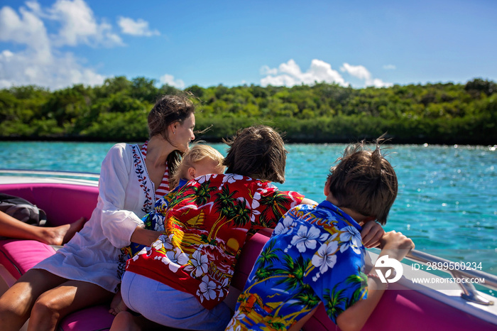 Happy beautiful fashion family, children and parents, dressed in hawaiian shirts, enjoying day trip with speed boat