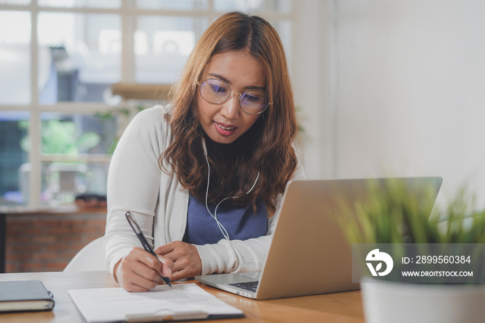 Asian people study online course via internet. Young girl watching business lesson from laptop computer and note lecture to notebook at home.