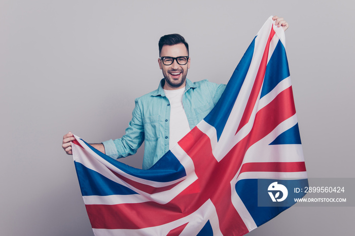 Portrait of attractive, handsome man in glasses and jeans shirt holding waving Jack Union flag