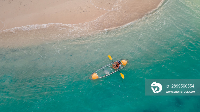 blue sea with floating transparent kayak near sand beach, person with life jacket on boat