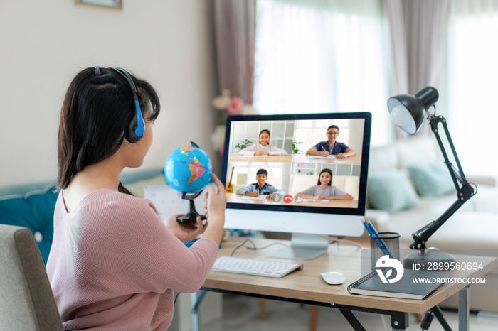 Asian woman teacher teaching geography via video conference e-learning and cheerful elementary school student looking at globe, Homeschooling and distance learning ,online ,education and internet..