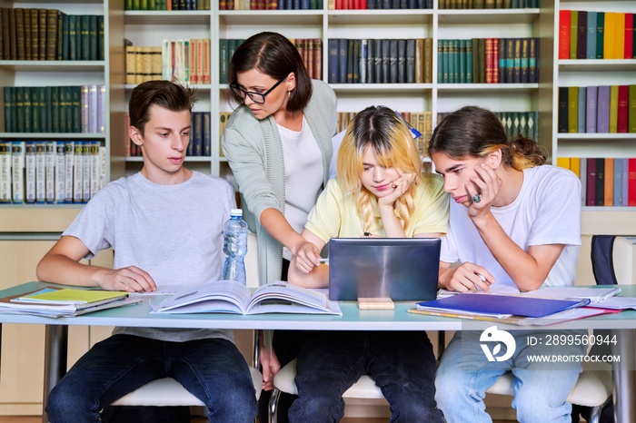 Group of teenage students studying in library class with female teacher mentor