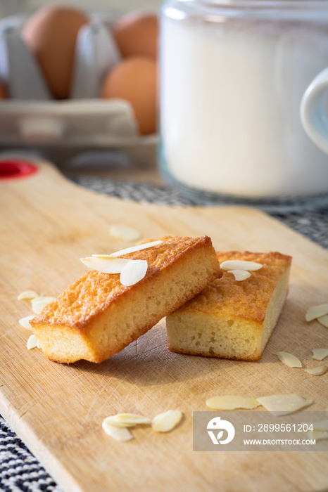 Gros plan sur des gâteaux financiers bien dorés sur une planche à découper parsemé d’amandes effilées