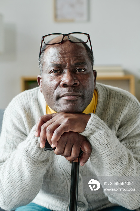 Portrait of African mature man leaning on his stick while resting at home and looking at camera