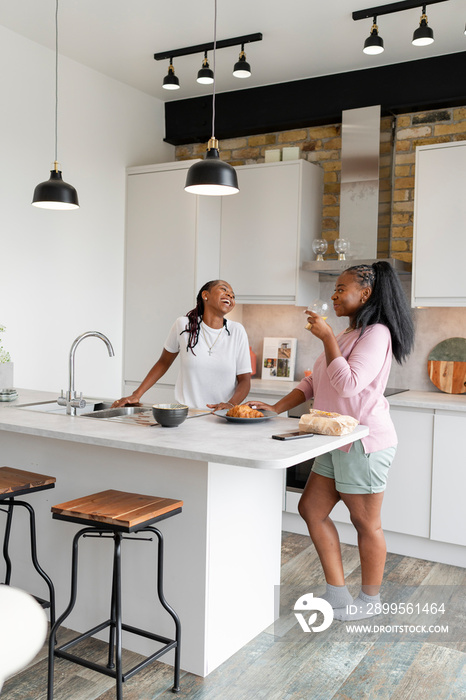 Lesbian couple chatting and eating in kitchen