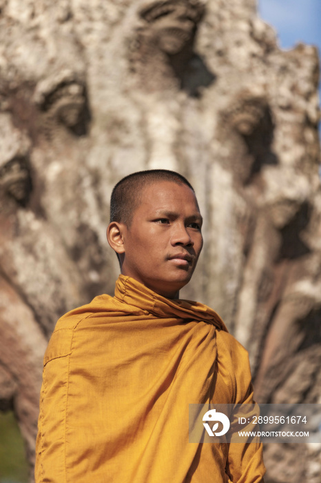 Young Buddhist monk standing outside temple in Angkor Wat, close up