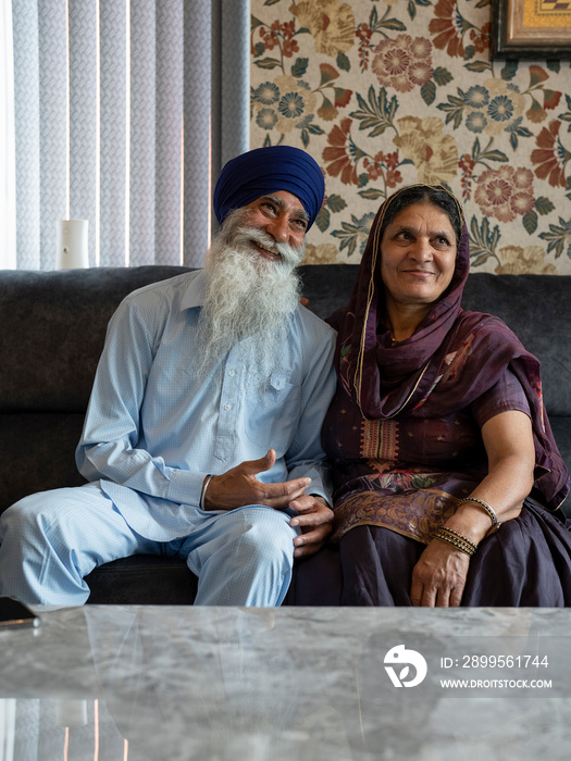 Senior couple in traditional clothing relaxing on sofa