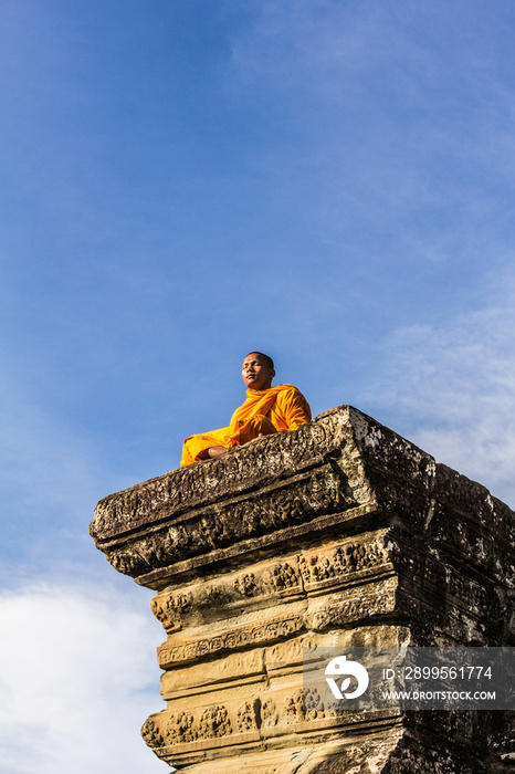 Young Buddhist monk sitting outside temple in Angkor Wat, Siem Reap, Cambodia