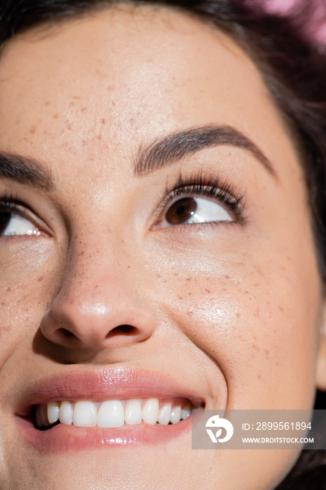 Cropped view of dreamy and freckled woman looking up.