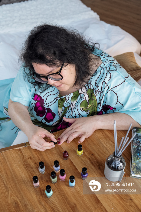 Plus sized female painting her nails at home