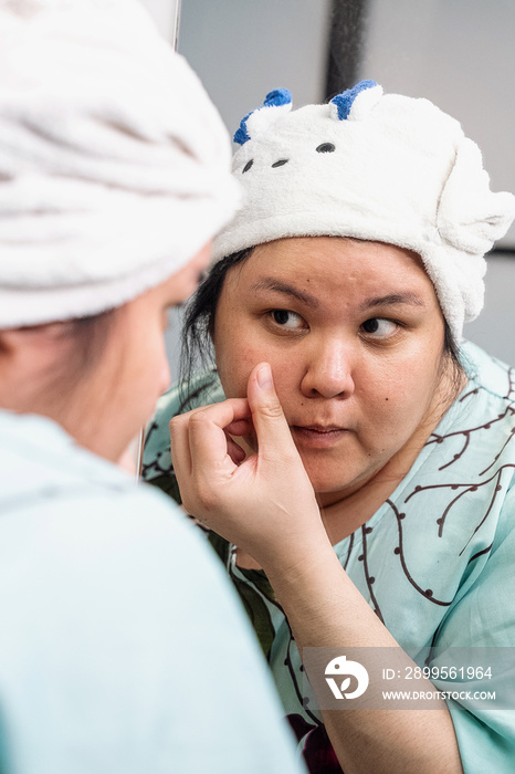 Plus size female examining her skin in the mirror