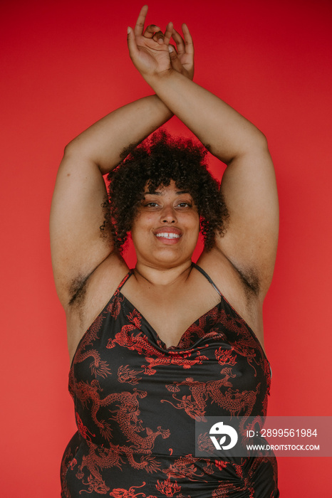 portrait of a plus size afro indigenous person arms crossed overhead smiling