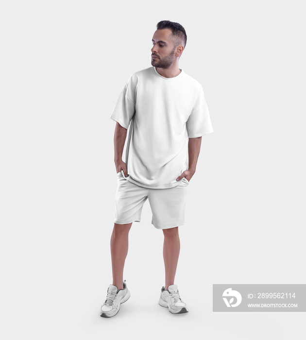 Oversized white t-shirt mockup, shorts on bearded guy in sneakers, with hands in pockets, front view, isolated on background.